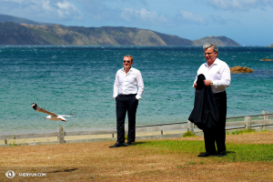 Från höger: Dirigent Milen Nachev, violinist Derek Hensler och en nyzeeländsk mås trotsar de starka vindarna som sveper över Fitzroy Bay. (Foto av dansaren Ben Chen)